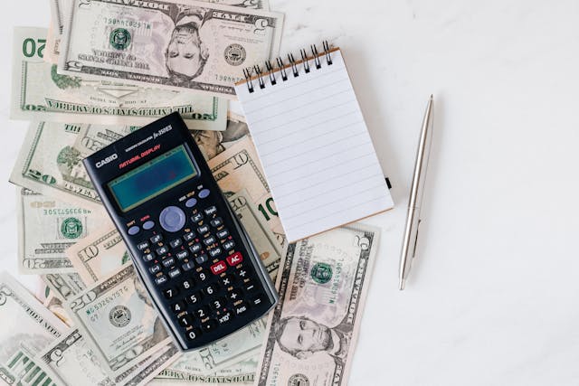 a calculator and notepad over cash